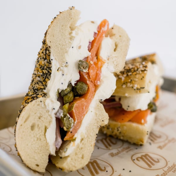 Everything bagel with cream cheese, smoked salmon, and capers on branded parchment paper.