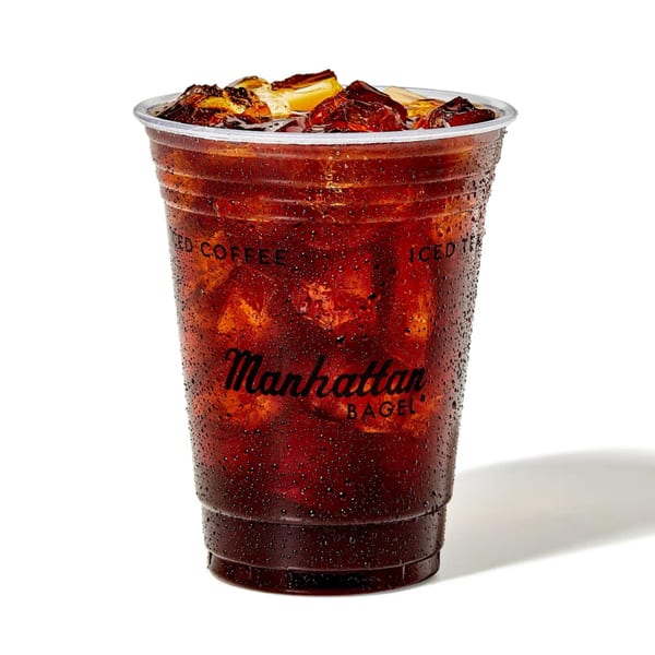 Manhattan Bagel iced coffee in a clear plastic cup with ice and condensation.