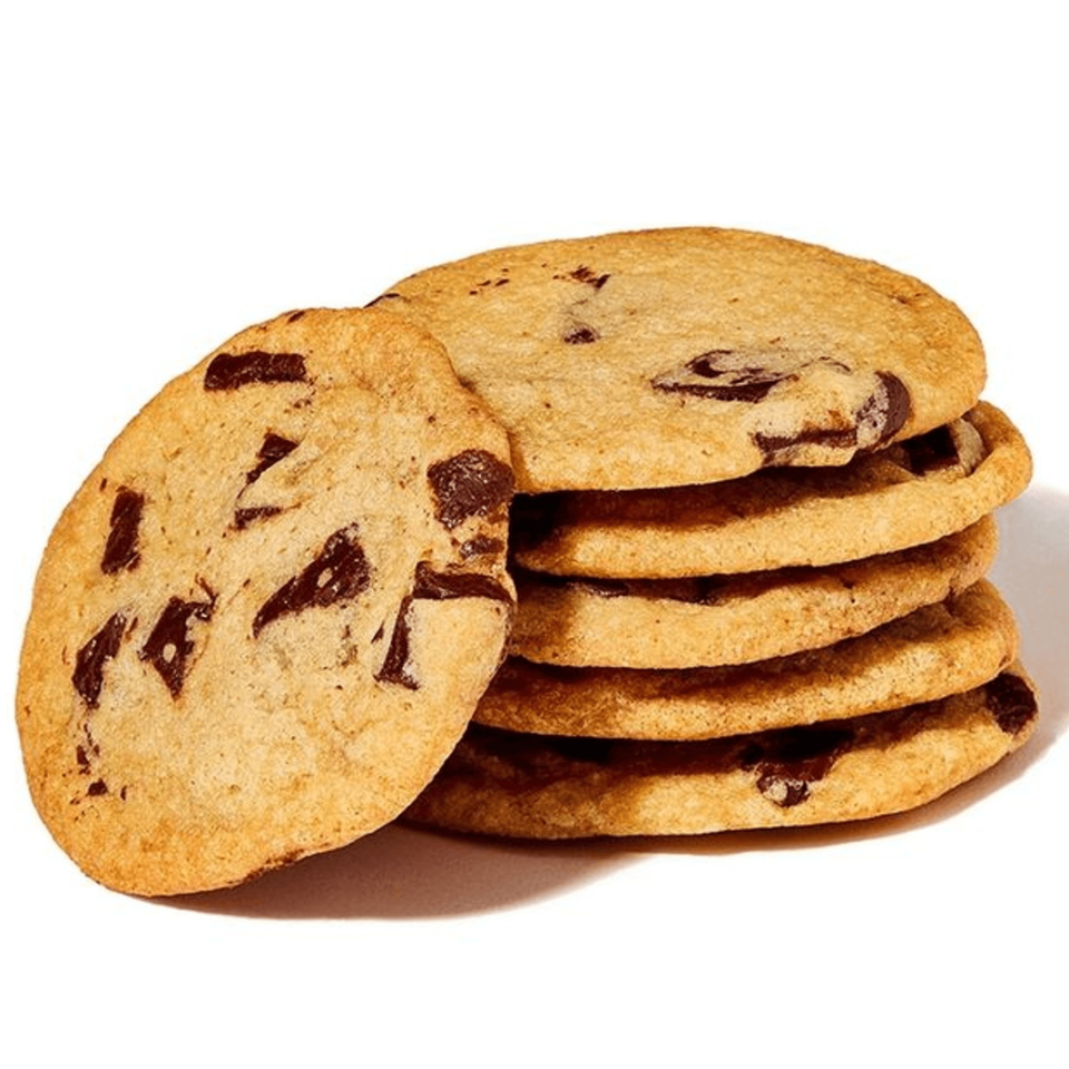 A stack of five chocolate chip cookies with one leaning against the side on a white background.
