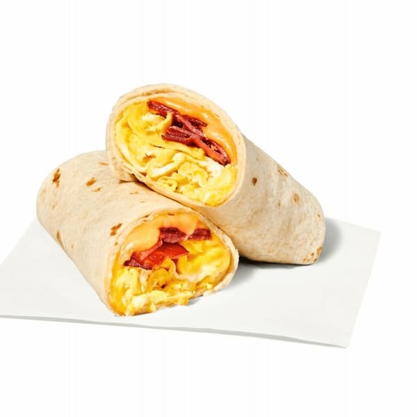 Two halves of a breakfast burrito filled with scrambled eggs, bacon, and melted cheese.